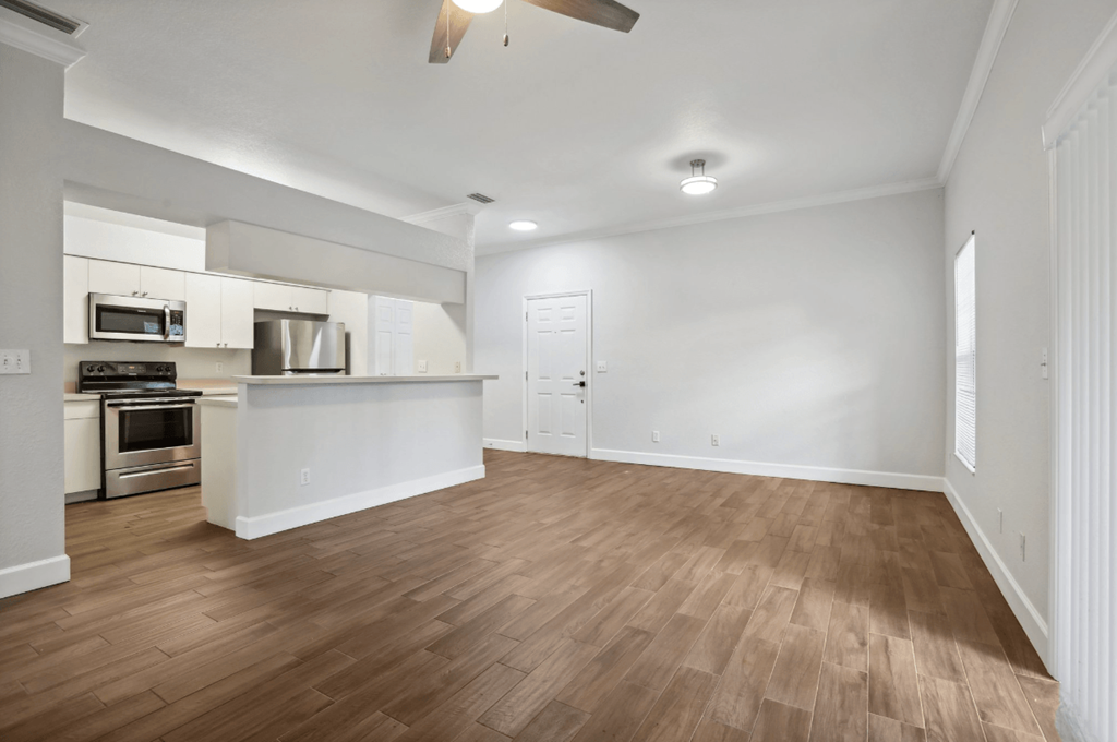 A kitchen with white cabinets and a wooden floor.